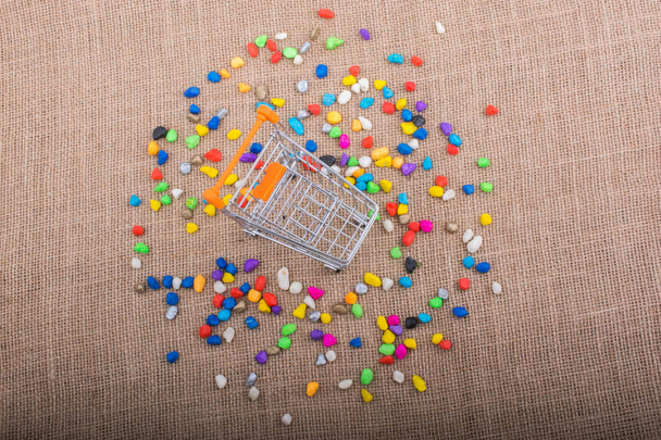 Little trolley amid Colorful pebbles on canvas background - Photo, Image