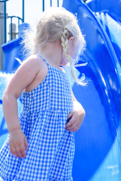 zbliżenie z dziewczyna w niebieskiej sukience, grając na niebieski slajdów w parku - Zdjęcie, obraz