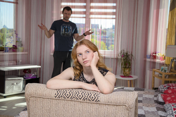 family conflict. Family conflict and the difficulties of the father and daughter in her room. The daughter sits right in front of the camera and looks unhappy - Fotoğraf, Görsel