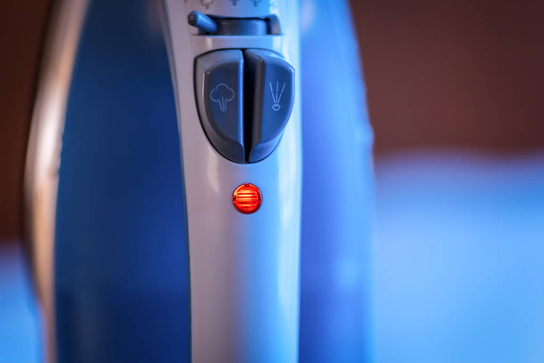 macro close-up de um ferro de mão sentado na posição vertical com luz de energia ligada
 - Foto, Imagem