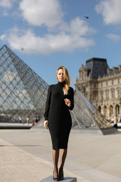 Tiny woman standing near Louvre and glass pyramind in black dress in Paris. - Фото, зображення