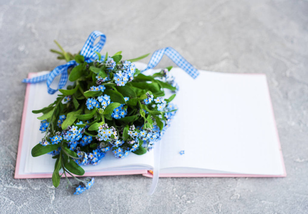 Forget me not flowers and notebook on grey stone background - Photo, Image