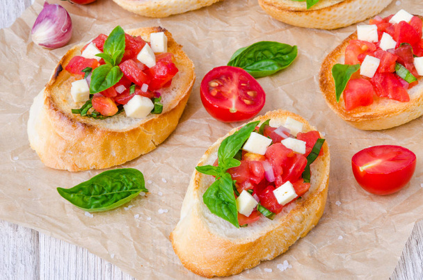 Bruschetta con tomate, cebolla, queso y albahaca fresca
 - Foto, Imagen