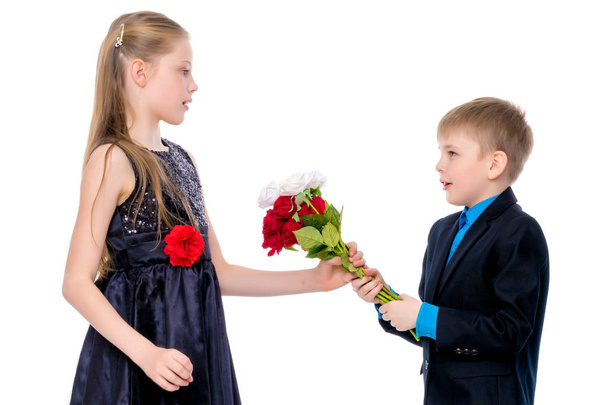 A little boy gives the girl flowers. - Фото, изображение