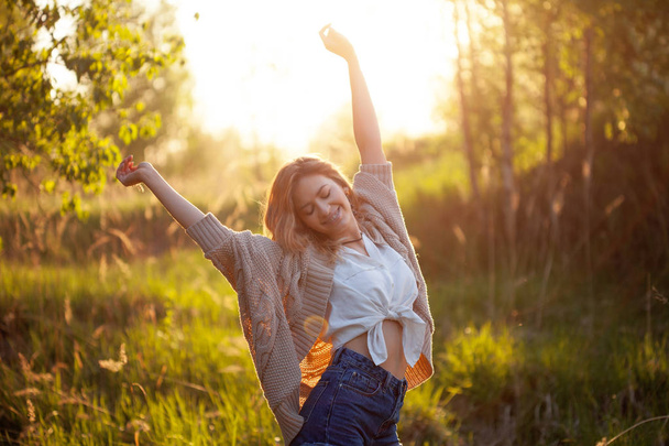 Cute charming girl in summer in the field. Young woman is happy and feels free outdoors - Foto, Imagen