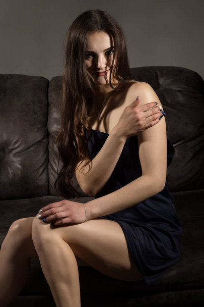 Sensual attractive young woman in a silk pajamas poses on a sofa. - Фото, зображення