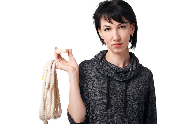 young woman posing with rope and soap in studio on white background, wearing brown shorts and shirt - Photo, Image