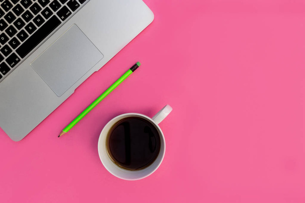 Laptop with coffee cup and green pencil on bright pink background - Valokuva, kuva