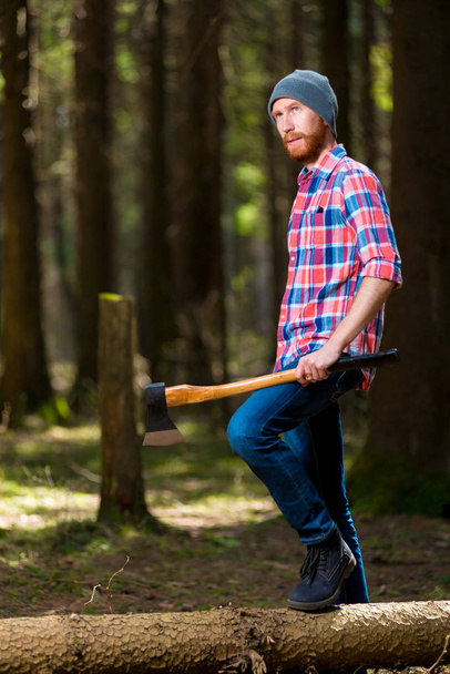 silvicultor pensativo com um machado perto de uma árvore despejada na floresta
 - Foto, Imagem