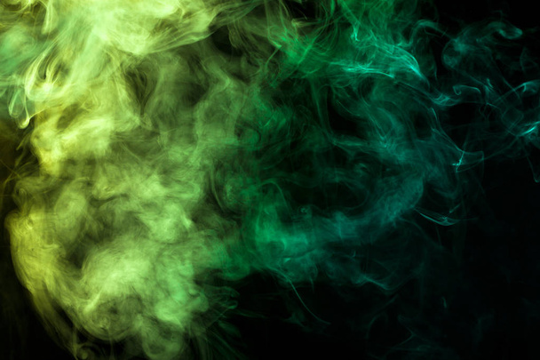 Gęsty dym colorful zielony i żółty na czarny na białym tle. Tło z dymu vape - Zdjęcie, obraz