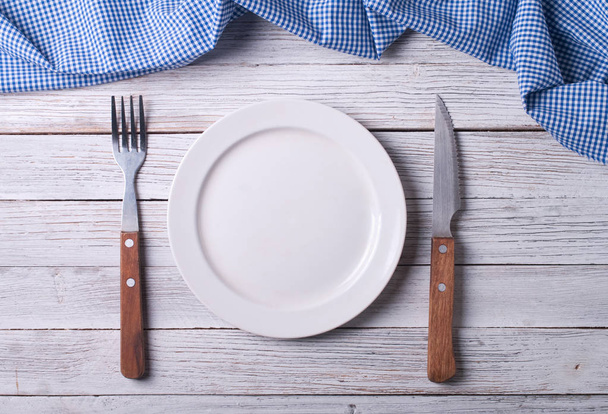 Пустая тарелка на скатерти на деревянном столе
 - Фото, изображение