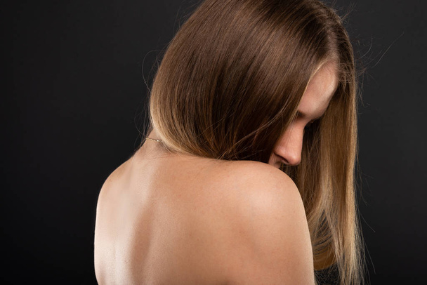 Porträt der schönen weiblichen Modell mit nackten Rücken sexy auf schwarzem Hintergrund mit Copypsace-Werbefläche - Foto, Bild