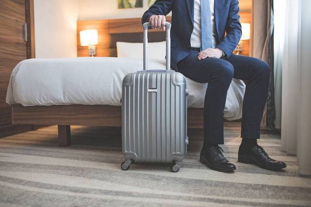 Молодой бизнесмен с чемоданом в спальне
 - Фото, изображение