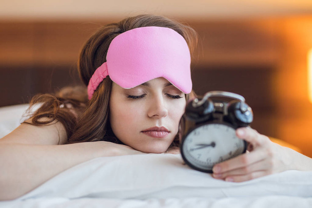 Sleeping young girl with a clock indoors - Фото, изображение
