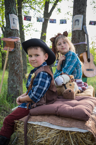 Смешные дети, одетые как ковбои с игрушечными лошадьми. Костюмная вечеринка
 - Фото, изображение