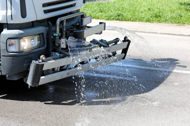 Camión de lavado de carreteras con salpicaduras de agua para lavar el asfalto
 - Foto, imagen