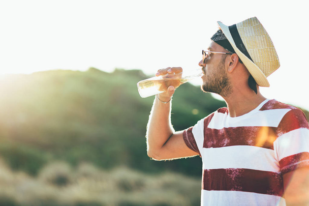 若い男がビーチでビールを飲む - 写真・画像