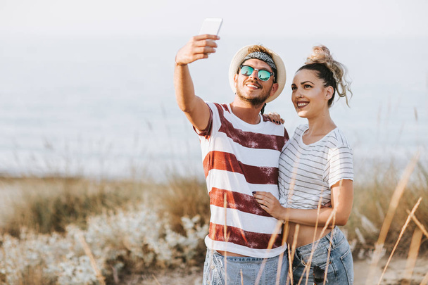 Giovane coppia prendendo selfie in spiaggia
 - Foto, immagini