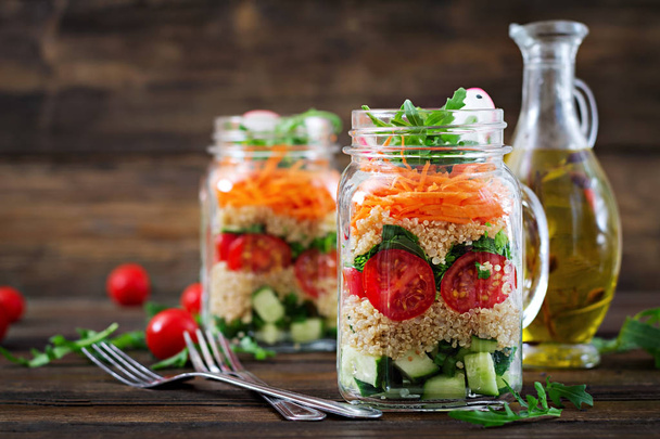 gros plan des salades de quinoa, roquette, radis, tomates et concombres dans des bocaux en verre sur fond en bois
 - Photo, image