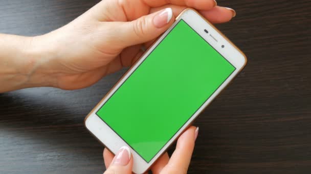 Γυναικεία χέρια με όμορφο γαλλικό μανικιούρ Πάρτε ένα λευκό smartphone με πράσινη οθόνη. Χρησιμοποιώντας το Smartphone, κρατώντας Smartphone με πράσινη οθόνη - Πλάνα, βίντεο