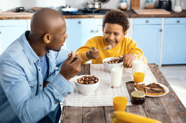 Joyful young father and his son having breakfast together - Valokuva, kuva
