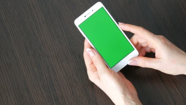 Женские руки с красивым французским маникюром возьмите белый смартфон с зеленым экраном. Использование смартфона, проведение смартфона с зеленым экраном
 - Кадры, видео