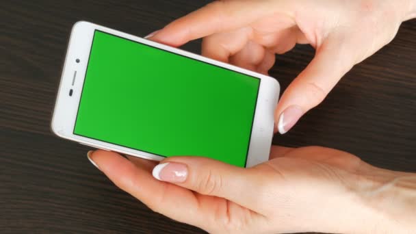 Γυναικεία χέρια με όμορφο γαλλικό μανικιούρ Πάρτε ένα λευκό smartphone με πράσινη οθόνη. Χρησιμοποιώντας το Smartphone, κρατώντας Smartphone με πράσινη οθόνη - Πλάνα, βίντεο