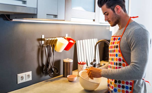 young man preparing food in modern kitchen at home - Фото, зображення