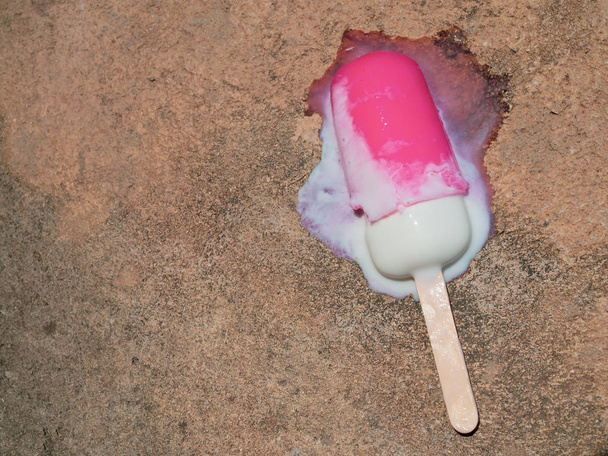 Ροζ Popsicle πάγο ποπ πτώση στο πάτωμα τσιμέντου και τήξης από το καυτό καλοκαίρι - Φωτογραφία, εικόνα