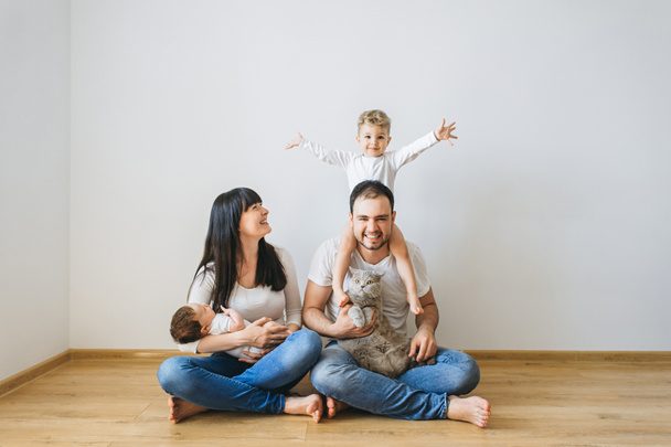 šťastná rodina s dvěma syny a šedé britská krátkosrstá kočka doma - Fotografie, Obrázek