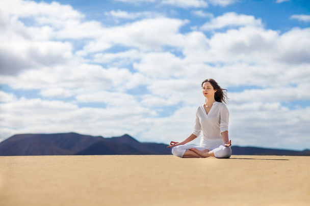 Young woman meditating in Lotus Pose in desert on Canary Islands, Spain. Padmasana. Relax concept - Foto, Imagem