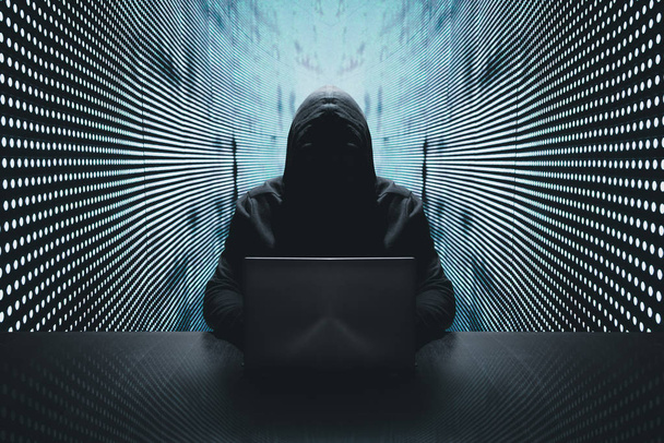 hacker anónimo en frente de su ordenador con fondo de pared de luz azul
 - Foto, imagen