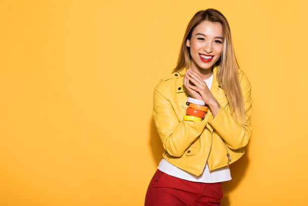 smiling young asian woman standing on yellow background  - Foto, Bild