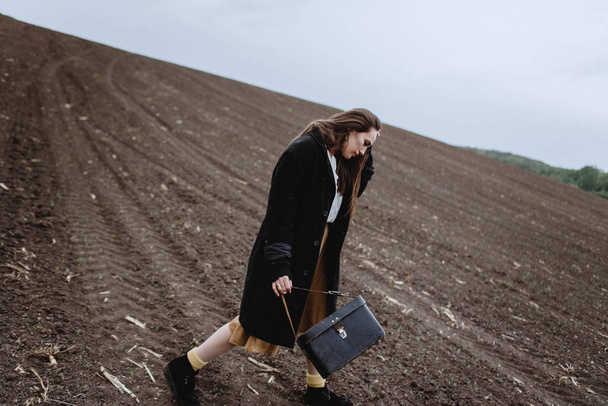 Vista lateral da mulher de casaco andando no campo e tocando o cabelo
 - Foto, Imagem
