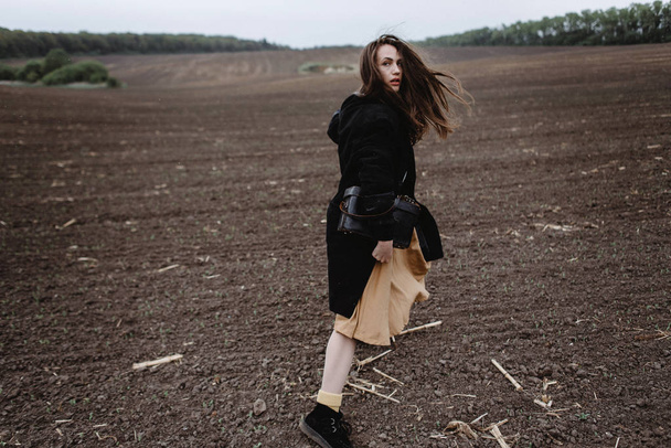 Visão traseira do modelo feminino posando em tempo ventoso no campo
 - Foto, Imagem