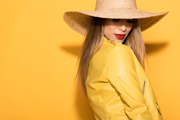 attractive asian female model in straw hat posing on yellow background  - Zdjęcie, obraz