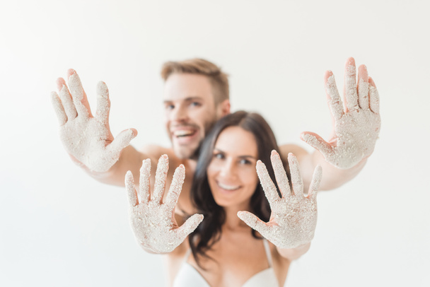selective focus of cheerful couple showing hands in sand, isolated on white, isolated on white - Fotografie, Obrázek