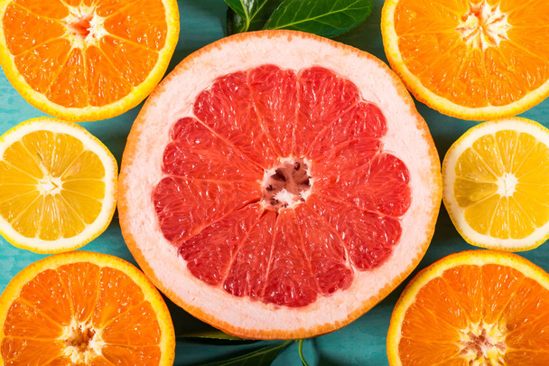 Sliced grapefruit, oranges and lemon. Citrus fruits collection on blue wooden background - Foto, imagen