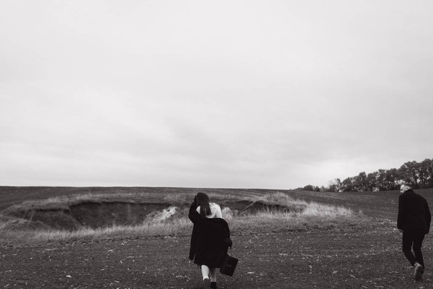 Vista en blanco y negro de la pareja caminando en el prado en el día frío
 - Foto, imagen
