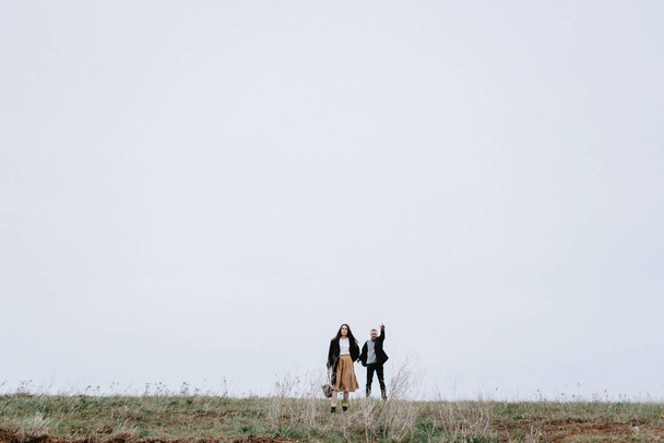 Täyspitkä näkymä pari kävely kylmänä päivänä niityllä
 - Valokuva, kuva