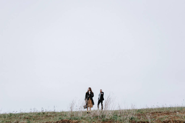 Volle lengte weergave van paar wandelen in koude dag op weide - Foto, afbeelding