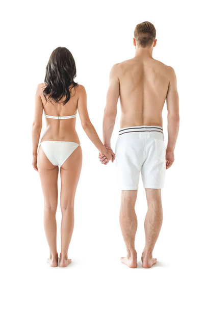 назад вид молодой пары в купальниках, держась за руки, изолированные на белом
 - Фото, изображение