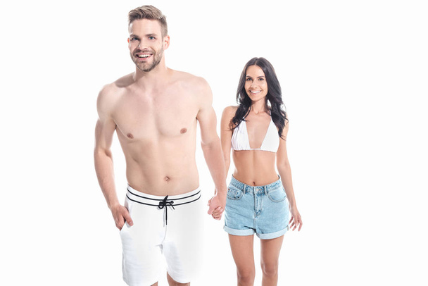 beautiful smiling couple in swimwear holding hands, isolated on white - Fotografie, Obrázek