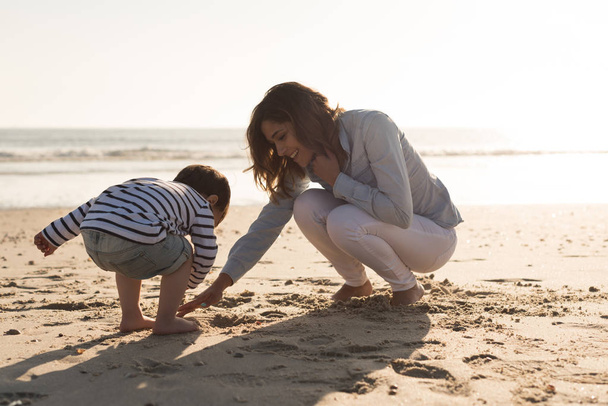 Young mother exploring the beach with toddler - Foto, imagen