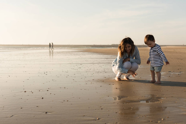 Jeune mère explorant la plage avec tout-petit
 - Photo, image