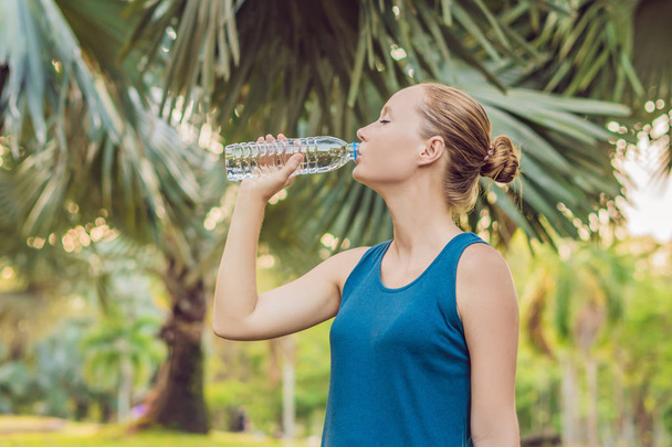 Attractive sporty woman drinking water from a bottle after jogging or running. - Valokuva, kuva