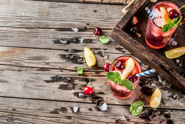Zomer iced verfrissing drankje, cherry cola limonade of mojito cocktail in hoog glas, op oude rustieke houten achtergrond kopie ruimte - Foto, afbeelding