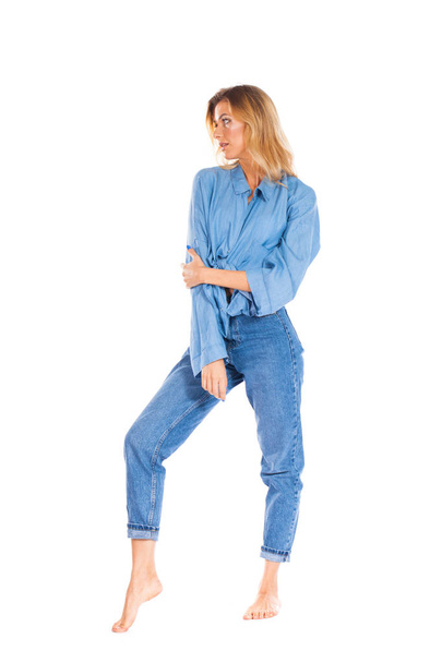 Full length portrait of a smiling cute young blonde woman in blue jeans standing isolated on a white background - Zdjęcie, obraz
