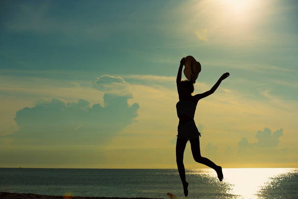 若いカップルの運動と早朝サンライズ ビーチでジャンプします。美しい黄色の空と - 写真・画像
