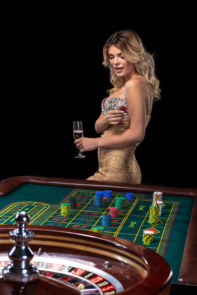 Fiatal szőke nő visel a gyönyörű szexi fényes ruha játszik rulettet a kaszinóban - Fotó, kép